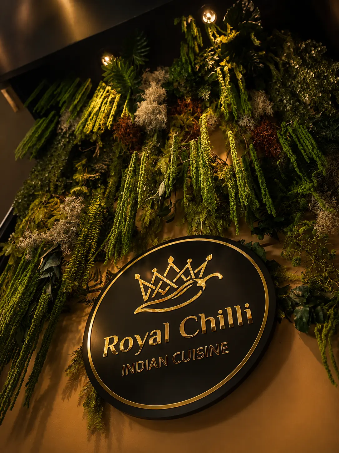 Rètol il·luminat de Royal Chilli envoltat de vegetació